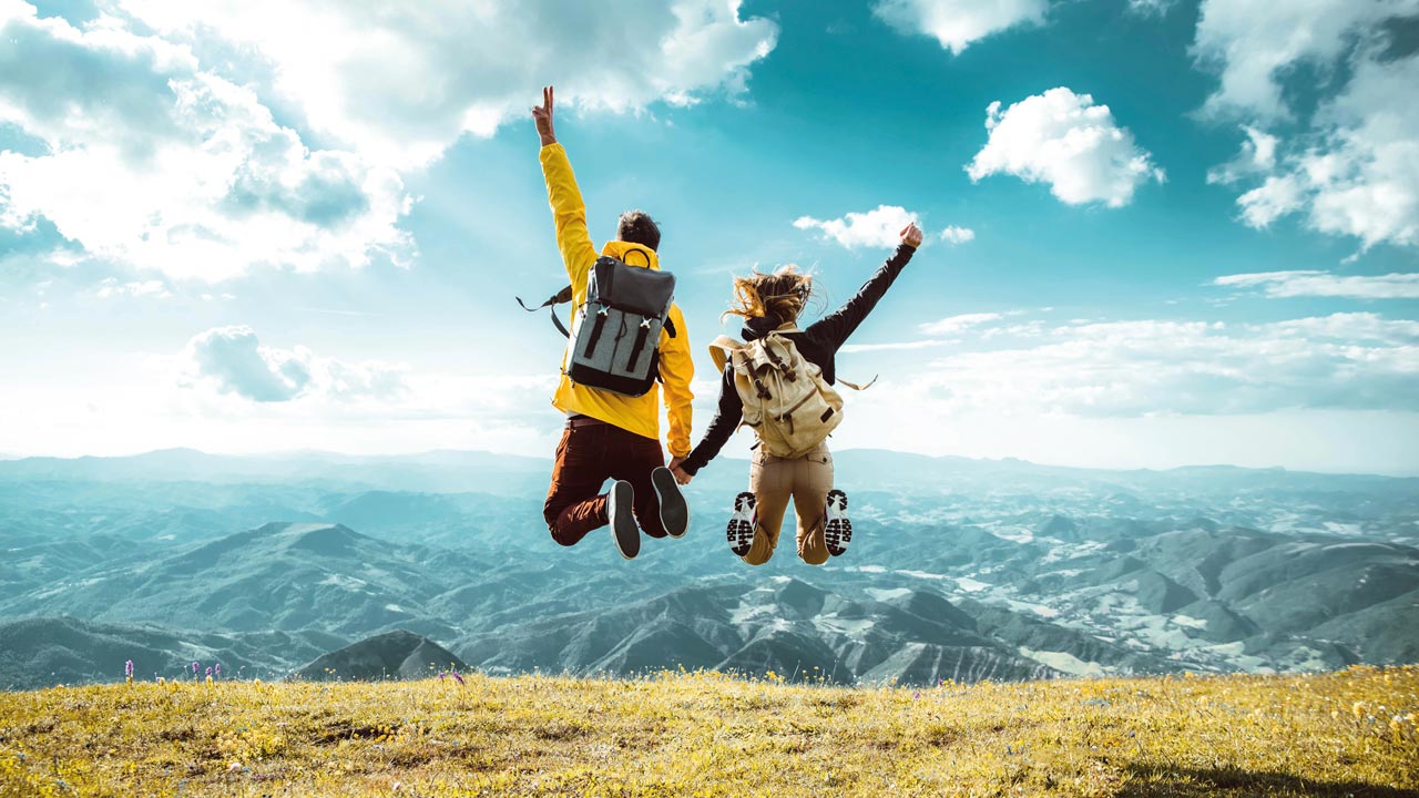 Zwei Schüler springen in die Luft. Im Hintergrund sind die Alpen zu sehen.