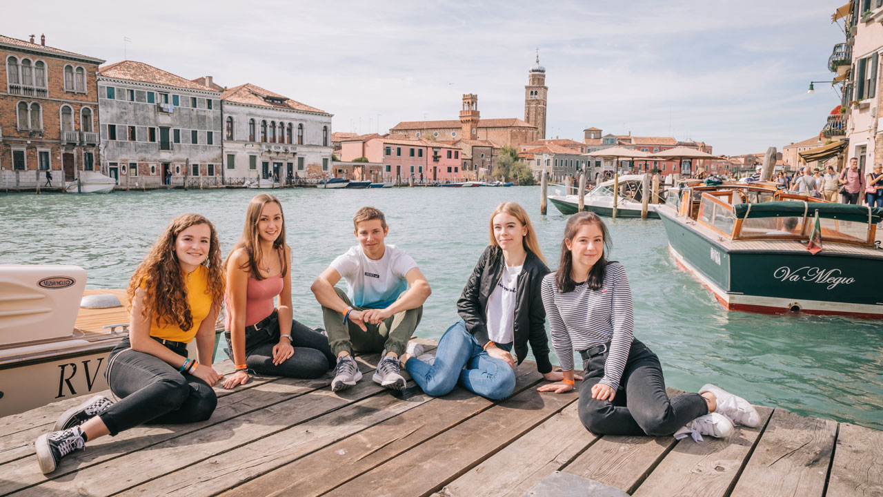 Schüler/innen sitzen auf einem Steg in Venedig